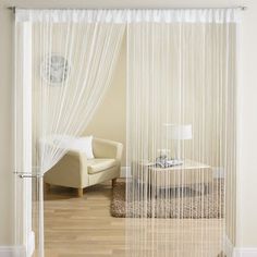 a living room with white curtains and a chair