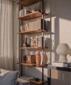 a living room filled with furniture and bookshelves on top of wooden shelves next to a window