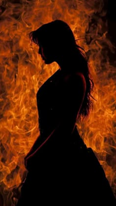 the silhouette of a woman standing in front of fire with her hand on her hip