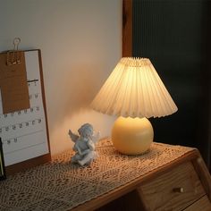 a lamp sitting on top of a wooden desk next to a calendar and an angel figurine