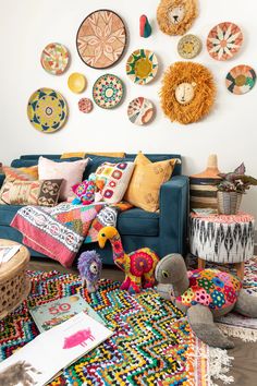 a living room filled with lots of colorful pillows and decorations on the wall behind a blue couch