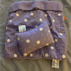 two pillows are laying next to each other on a bed with purple sheets and yellow flowers