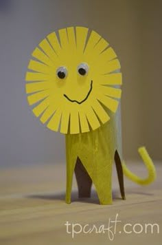 a yellow lion made out of paper on top of a wooden table next to a wall