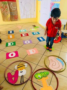 a young boy standing on top of a floor next to some cut out letters and numbers