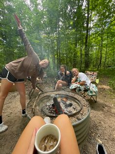 a group of people sitting around a fire pit with drinks in front of them on the ground