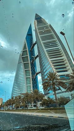 some very tall buildings in the middle of a city with palm trees and water droplets on them