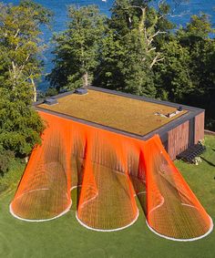 an aerial view of a house with orange coverings on the grass and trees surrounding it