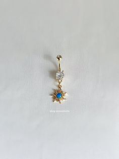 a gold belly ring with a blue stone in the center and a star dangling from it's side