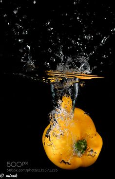 a yellow pepper with water splashing on it