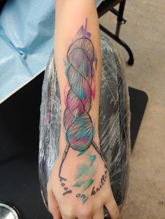 a person with a tattoo on their arm holding a ball of yarn in her hand