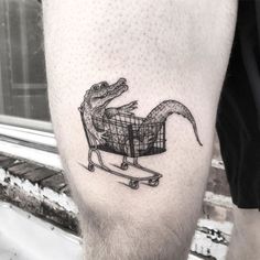 a man's leg with a small alligator in a shopping cart tattoo