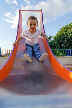 a little boy sitting on top of a slide