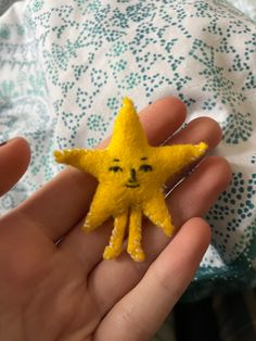 a hand holding a small yellow star with a face drawn on it's side