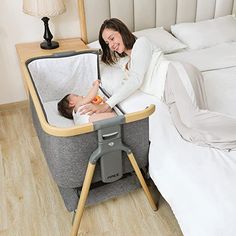 a woman laying on top of a bed next to a baby in a crib