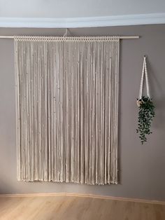 a wall hanging on the side of a gray wall next to a wooden floor with a plant in it