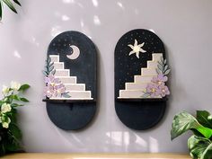 two decorative wall hangings with flowers and stars on them next to a potted plant