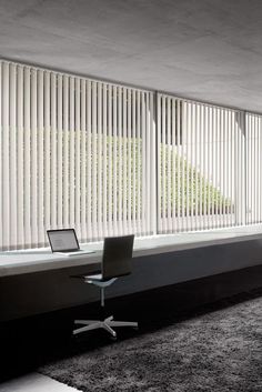 a chair and table in front of a window with vertical blinds on the outside wall