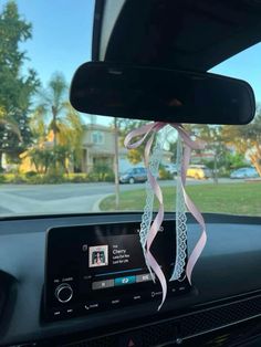 a car dashboard with a pink ribbon hanging from the dash