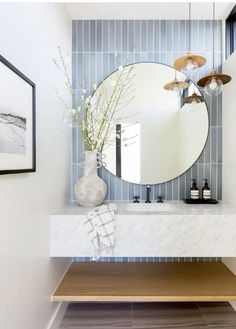 a bathroom with a large round mirror on the wall and a wooden bench in front of it