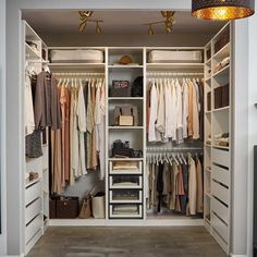 an open closet with clothes hanging on the walls and drawers, along with other items