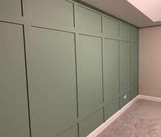 an empty room with green paneled walls and carpet