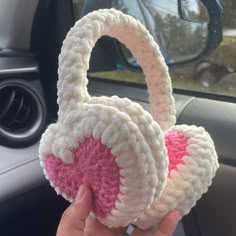 someone is holding up a crocheted ear muffs in their car's dashboard