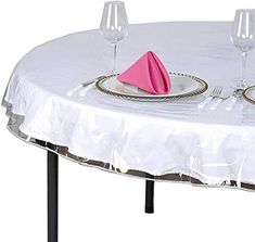 a white table topped with two wine glasses and a pink napkin on top of it