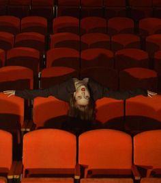 a woman with her head above the seat in an empty auditorium