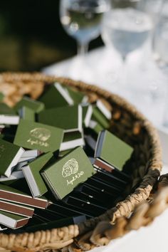 a basket filled with green and white cards on top of a table next to wine glasses