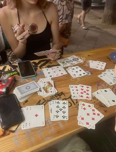 two women sitting at a table with cards and cell phones on it while one woman holds up her phone