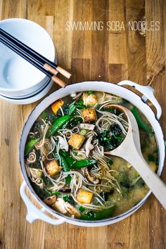 an overhead view of a bowl of soup with chopsticks on the side and another bowl in the background