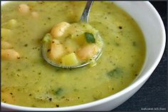 a white bowl filled with broccoli and shrimp chowder on top of a table