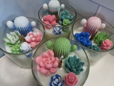 four glass bowls filled with different types of fake flowers