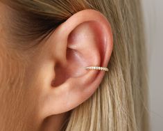 a woman's ear with a single diamond bar in the middle