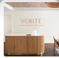 a white counter top sitting in front of a wooden chair next to a wall with the words verite on it