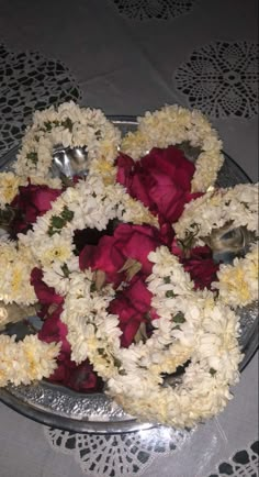 white and red flowers are arranged on a silver platter with serving utensils