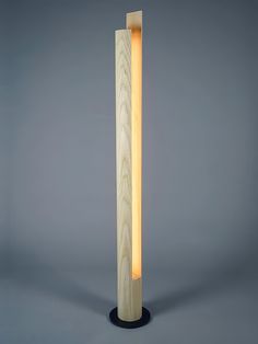 a tall wooden lamp with a dim light on it's side and the base is made out of wood