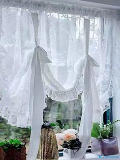 two vases with flowers are sitting on a window sill in front of the curtains