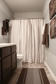 a bathroom with a toilet, sink and shower curtain in it's center area