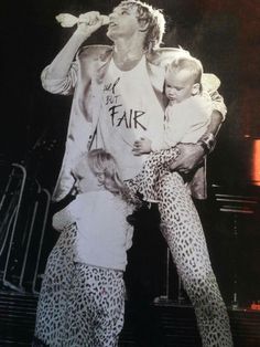 a man holding two children while standing on stage