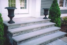 a set of stone steps leading up to a house with two urns on each side