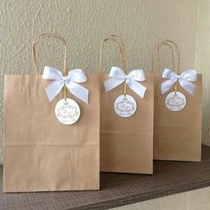 three brown paper bags with white bows and tags on them, sitting on a shelf