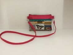 a small purse sitting on top of a white table next to a red bag with butterflies on it