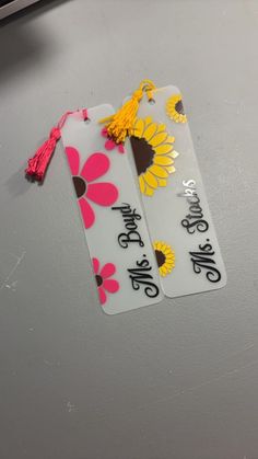 two tags with flowers and tassels on top of a refrigerator freezer door