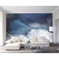 a living room with white furniture and a large painting on the wall