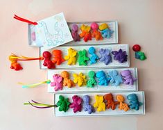 three boxes filled with different colored plastic animals on top of a pink table next to each other