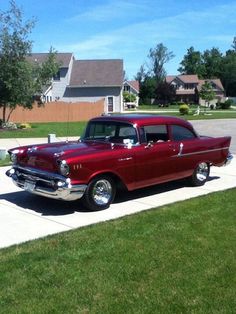 an old red car is parked on the sidewalk