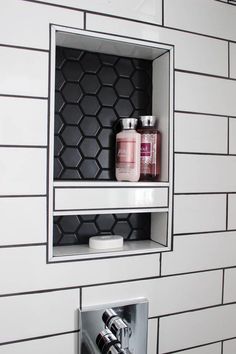 a bathroom with black and white tiles on the wall, two shelves above the toilet paper dispenser