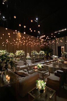 a room filled with lots of white flowers and lights hanging from the ceiling above it