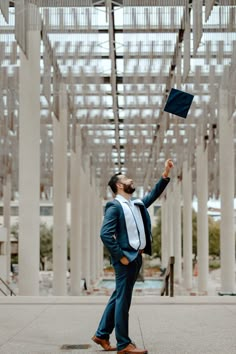 a man in a suit throwing a graduation cap into the air